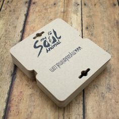 a close up of a business card on a wooden surface with the word saj journal written in black