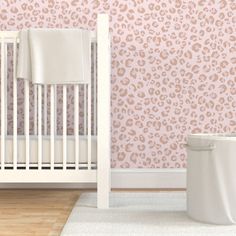 a white crib in front of a pink wallpaper