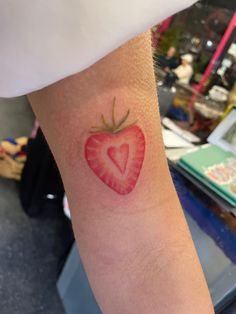 a heart shaped strawberry tattoo on the arm