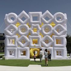 two people are walking in front of a building made out of fake white and yellow objects