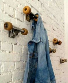 an old pair of jeans hanging on a brick wall with skateboard wheels attached to it