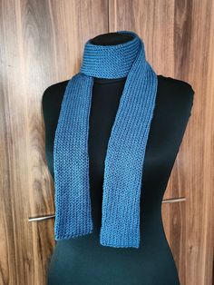 a blue knitted scarf sitting on top of a mannequin