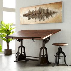 a dining table with two stools and a painting on the wall above it in a room