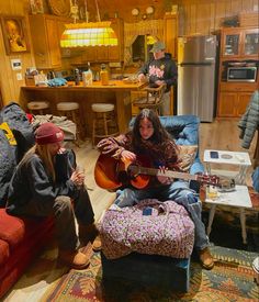 two people sitting in a living room playing guitars