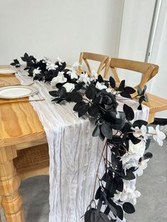 the table is set with black and white flowers on it, along with a wooden chair