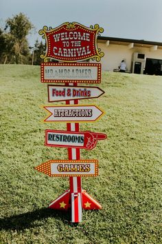 a sign in the grass that says welcome to carnival and attractions with other signs on it