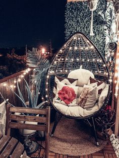 a chair with pillows and lights on top of a wooden deck next to a plant