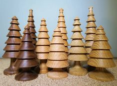 several wooden christmas trees lined up in a row on top of a carpeted floor