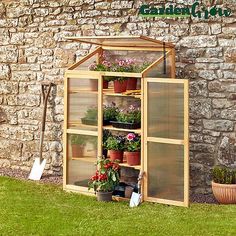 a small wooden greenhouse with plants growing inside