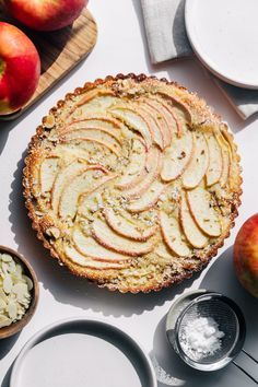 an apple pie is on the table with apples and other ingredients to make it look delicious