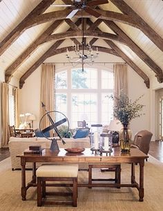 a living room filled with lots of furniture and a wooden table in front of a large window