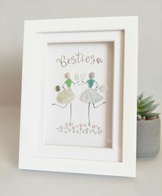 a white frame with two birds holding hands and the words besties are in front of a succulent plant