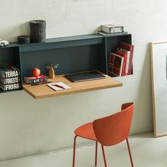 a desk with some books on it and a chair in front of the wall next to it