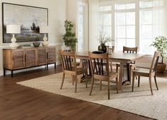 a dining room table and chairs in front of a large window with potted plants