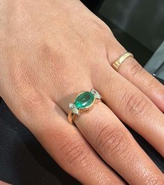 a woman's hand with an emerald and diamond ring