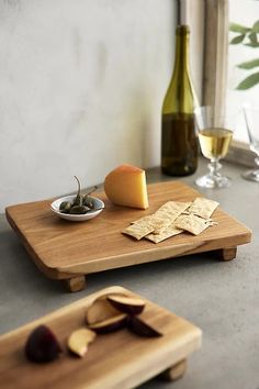 a wooden cutting board topped with an apple and crackers next to a bottle of wine