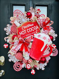 a christmas wreath with candy canes, hot cocoa and a mug on it's front door