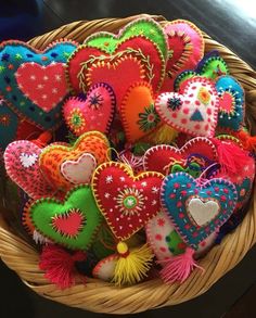 a basket filled with lots of different colored heart shaped pillows on top of a table