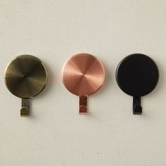 three different types of round metal objects on a white surface, one black and one gold