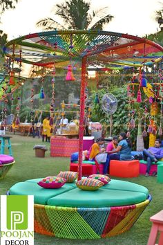 an outdoor seating area with colorful furniture and decorations on the grass, surrounded by palm trees