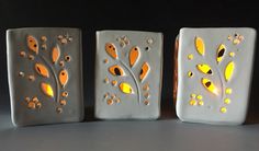 three white vases with yellow and black designs on the sides, one has a candle in it