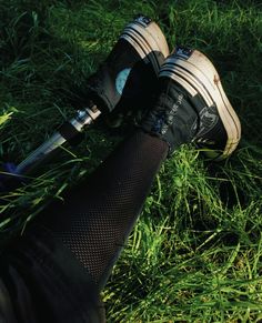 a person standing in the grass with their feet up and holding an umbrella over their head