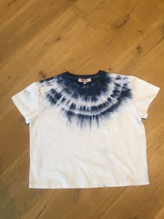 a white and blue tie - dyed t - shirt laying on top of a wooden floor