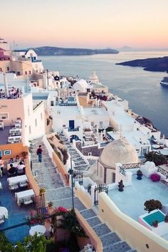 an aerial view of the ocean and buildings in oia, with people walking up stairs