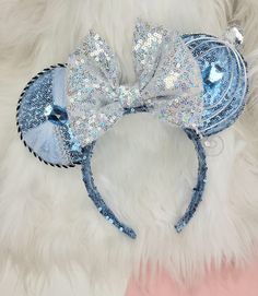 a blue and silver mouse ears with sequins on it, sitting on a fluffy white surface