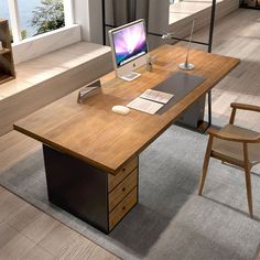 an office desk with a computer on it in front of a window and stairs leading up to the second floor