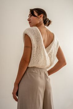 Handcrafted in our premium kid mohair blend, the Mohair Wrap Vest is incredibly soft, lightweight, and airy. Its reversible design offers multiple styling options, featuring a sleek boatneck on one side and a deep V-neck on the other. Wraps at the side for a flattering, form-enhancing fit. Whether paired with a turtleneck or worn solo, it effortlessly transitions between seasons. Wear it as a backless statement piece or switch to the V-neck side for a more casual look. A versatile, hand-knit ves Gilet Mohair, Mohair Top, Mohair Vest, Wrap Vest, White Vest, Western Outfits Women, Vest Designs, Vest White, Vest Outfits