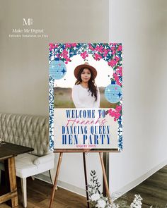 a welcome sign is displayed in front of a white couch and wooden easel with flowers on it