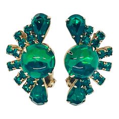 Midcentury Dark Emerald Green Cabochon Crystal Rhinestone Fan-Shape Clip Earrings, Matching necklace sold separately. Each earring features one large emerald green cabochon with two teardrop cut rhinestones bookending a fanned out row of square cut rhinestone pairs with neatly welded back and hinge clip. Top teardrop stone is backless. Cabochon rhinestone has a watery effect in how it catches the light and is one of the most striking characteristics of this earring. When I see jewelry like this, I can't help but think back to the 1950s and how glamorous some of the films were. There was something magical about films from that era and the fact that whenever they shot to the leading Lady, the camera would go a bit hazey, creating a bit of romance. What was your favorite film from that era? M Dark Emerald Green, Earrings Matching, Square Cut, Clip Earrings, Matching Necklaces, Green Crystals, Crystal Rhinestone, Emerald Green, Clip On Earrings