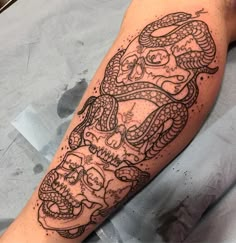 a black and white tattoo on the arm of a man with two snakes around his head