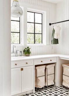 a kitchen with white cabinets and black and white floor tiles on the floor, along with three bins for storage