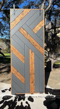 a wooden paneled door sitting on top of a cement ground next to a tree