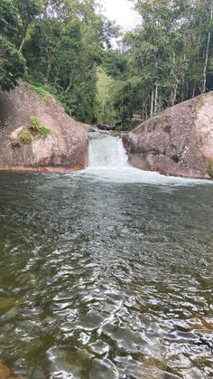 there is a small waterfall in the middle of the river with rocks on both sides