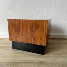 a wooden box sitting on top of a hard wood floor next to a white wall