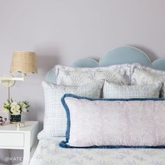 a bed with blue headboard and pillows on top of it next to a night stand