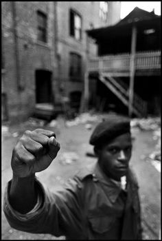 a black and white photo of a man pointing at the camera with his fist raised