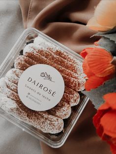 a close up of a pastry in a plastic container on a table with flowers behind it