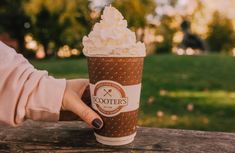 a person holding up a cup with whipped cream on it