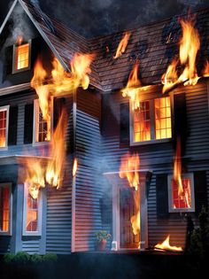 a fire blazing in front of a house with lots of flames coming out of the windows