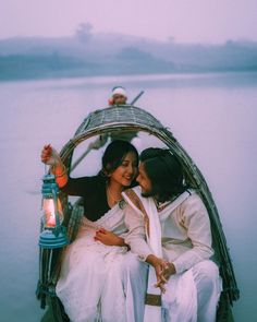 two women are sitting in a boat on the water and one is holding a lantern