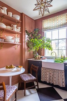 a kitchen with pink walls and black and white checkered flooring, potted plants on the window sill