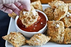 someone dipping something into a small bowl of sauce on some breaded pastries that are sitting on a white plate