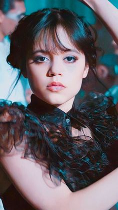 a young woman is posing with her hair blowing in the wind and wearing a black dress