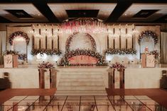 an elaborately decorated stage set up for a wedding ceremony with floral arrangements and chandeliers