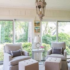 a living room filled with furniture and a chandelier hanging over it's windows