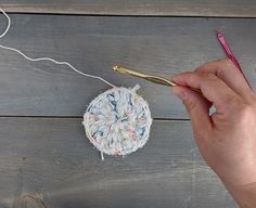 someone is crocheting something on the table with yarn and a knitting needle in their hand